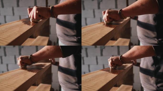 细木工将木材浸渍应用于木材产品。一个人用油盖住木架子。一名男子用木油盖住木架