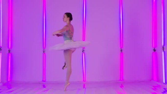 一位优雅的芭蕾舞演员在明亮的霓虹灯的背景下，在工作室里跳古典芭蕾舞。女孩进行垂直分裂，舞步和旋转。慢