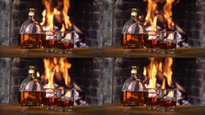 壁炉火背景下的威士忌或白兰地酒瓶和玻璃杯