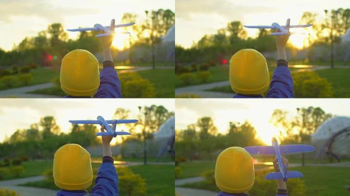 快乐的小男孩在日落时手持玩具飞机在公园里。孩子在户外夏天玩飞机。小飞行员梦想飞行，旅行度假幸福家庭大