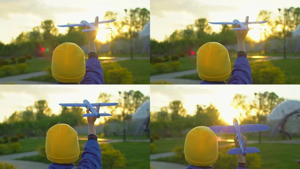快乐的小男孩在日落时手持玩具飞机在公园里。孩子在户外夏天玩飞机。小飞行员梦想飞行，旅行度假幸福家庭大