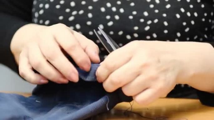 才华横溢的女裁缝师用纺织品缝制衣服。缝纫过程的特写视图。光线模糊背景