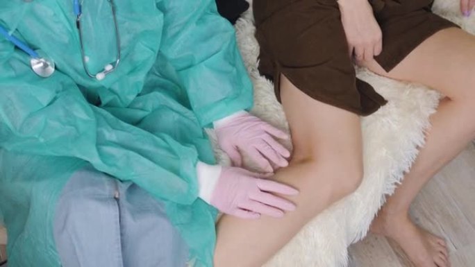 一名戴着医用手套的医生感觉到一名女性患者受伤的膝盖。