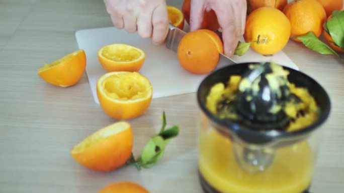 男人切成一半新鲜多汁的橘子。榨汁