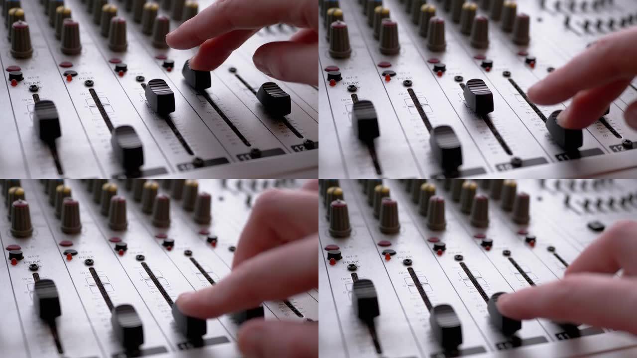 录音师，DJ在录音棚用手指在调音台上移动滑块