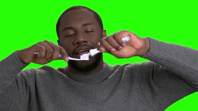 皮肤黝黑的男人在牙刷上涂牙膏。