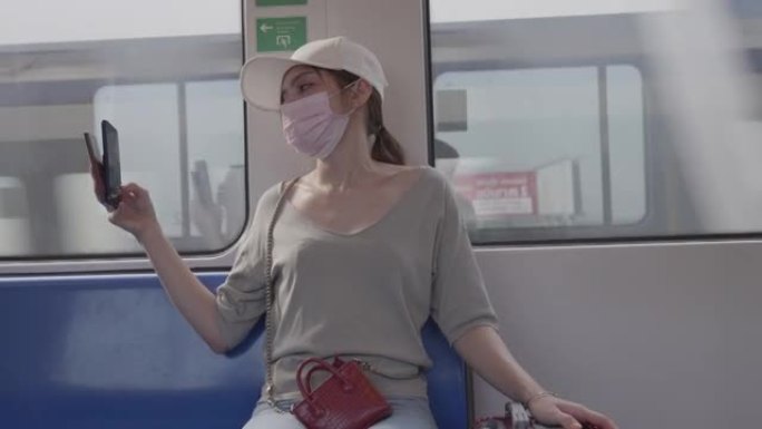 戴着冠状病毒面具的女旅行者在去机场的路上坐在火车上睡着了。