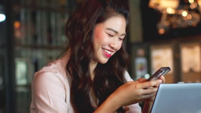 美丽迷人的亚洲女商人在咖啡店使用手机或智能手机咖啡馆通过社交媒体和在线购物微笑和幸福，温暖的语气