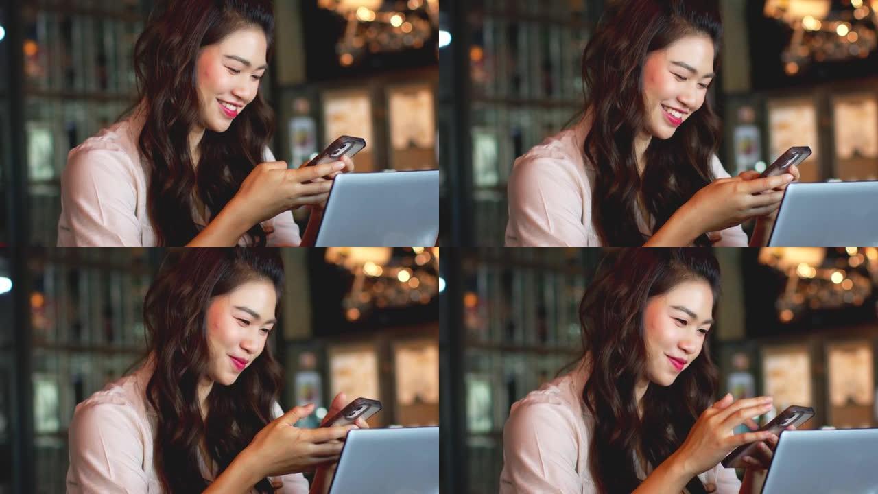 美丽迷人的亚洲女商人在咖啡店使用手机或智能手机咖啡馆通过社交媒体和在线购物微笑和幸福，温暖的语气