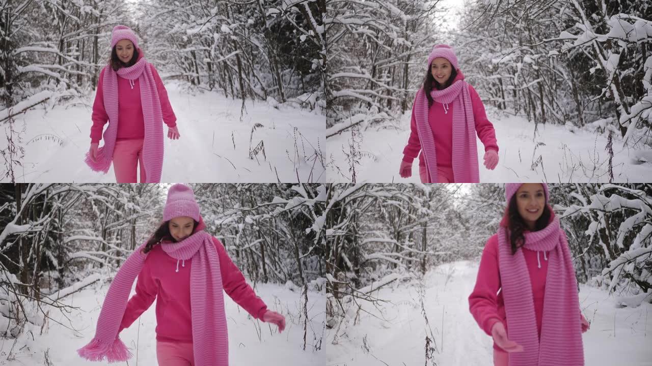 穿着粉红色衣服的女人戴着扎好的帽子和围巾穿过雪地