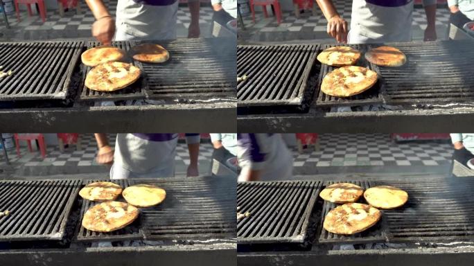 面包蛋糕用木炭油炸。一个人把面包放在烤架上。油炸产生的烟雾