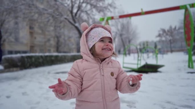 好奇的蹒跚学步的女孩吃雪，同时在冬季魔术期间与家人一起玩耍