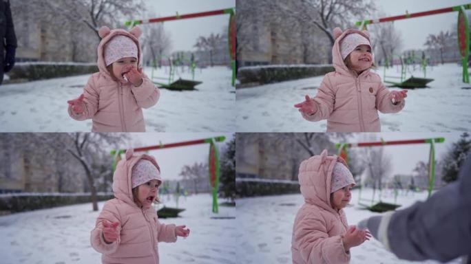 好奇的蹒跚学步的女孩吃雪，同时在冬季魔术期间与家人一起玩耍