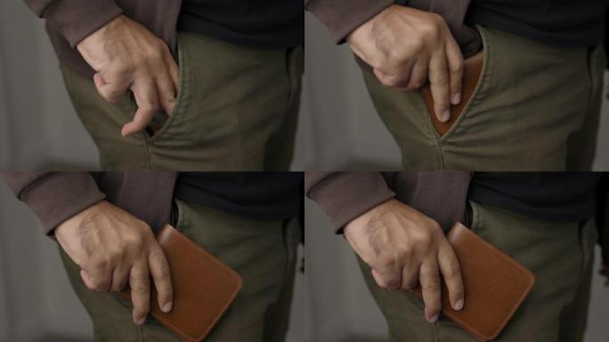 关闭男性的手从他的牛仔裤口袋里拿出钱包。展示钱包。金融业务概念。
