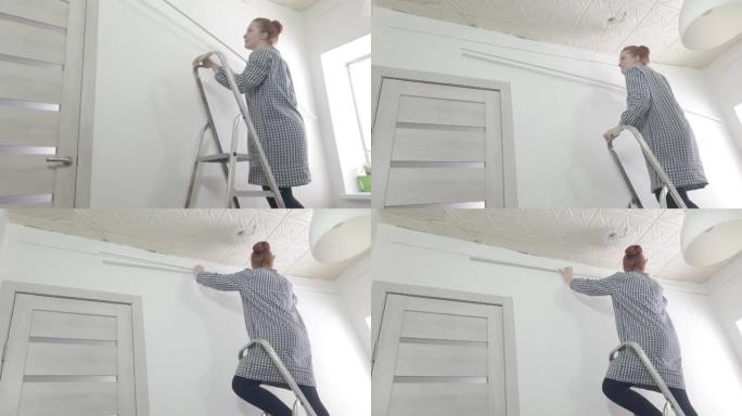 一名妇女爬上梯子，在天花板底座上尝试伸展天花板，用自己的双手修理