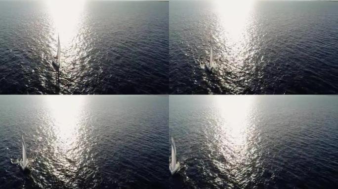 帆船在阳光的照射下在海中航行。我们可以看到船和水在地平线上的整个和光线的反射-用无人机4K鸟瞰图