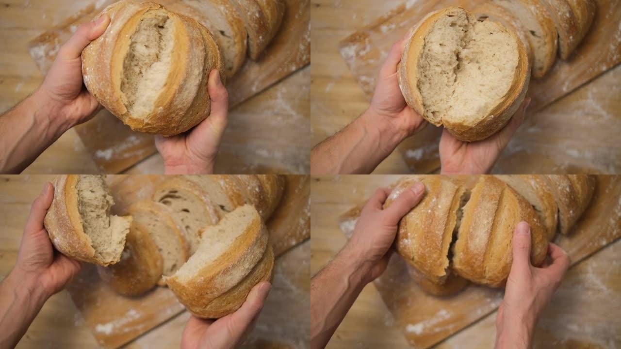 一个男人在厨房里打碎面包。相机上新鲜出炉的新鲜面包破裂 ..顶视图。木桌。4k分辨率选择性聚焦的烹饪