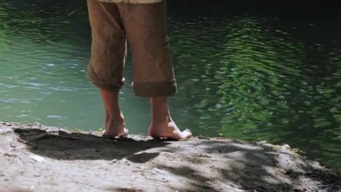 两个男孩穿着脏衣服，光着脚在河岸上闲逛。