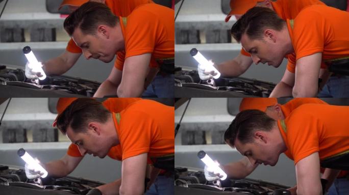 机械师经理在汽车维修服务中心的车间里用手电筒和助理工人一起检查汽车。两辆汽车工程师小组检查车辆详细信