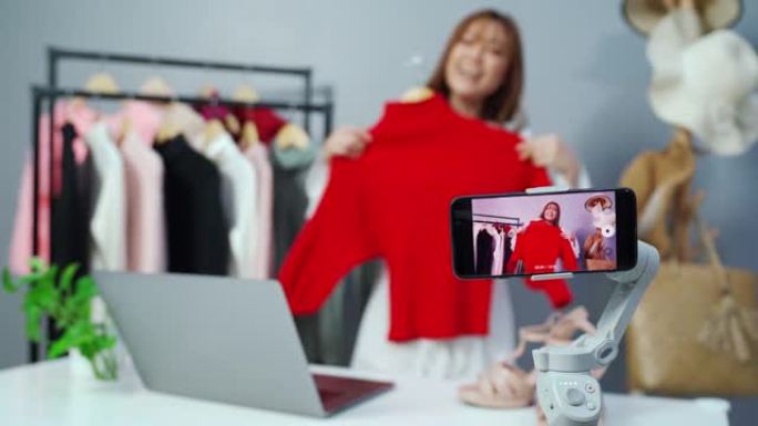 年轻女子通过智能手机直播在线卖衣服，在家商务在线电子商务