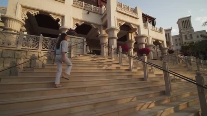 女人走上迪拜豪宅的楼梯。阿拉伯联合酋长国豪华住宅区一名妇女的街景