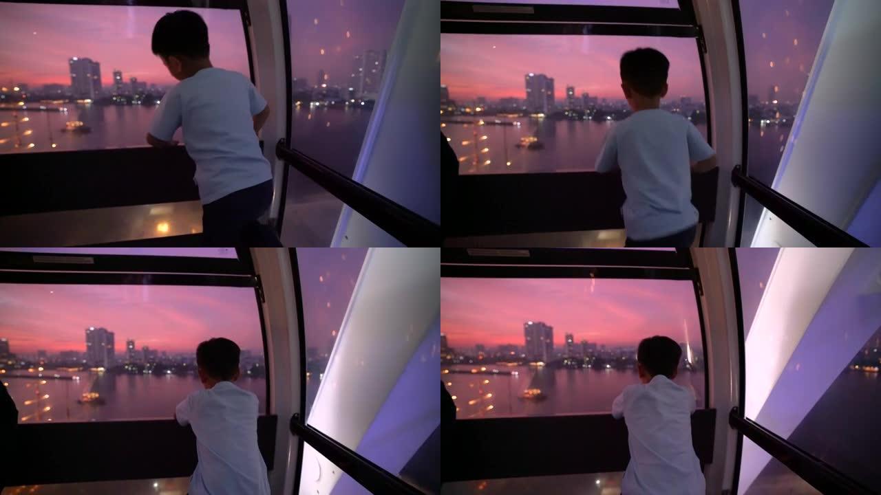 曼谷晚上摩天轮上的亚洲孩子。度假和梦想的概念