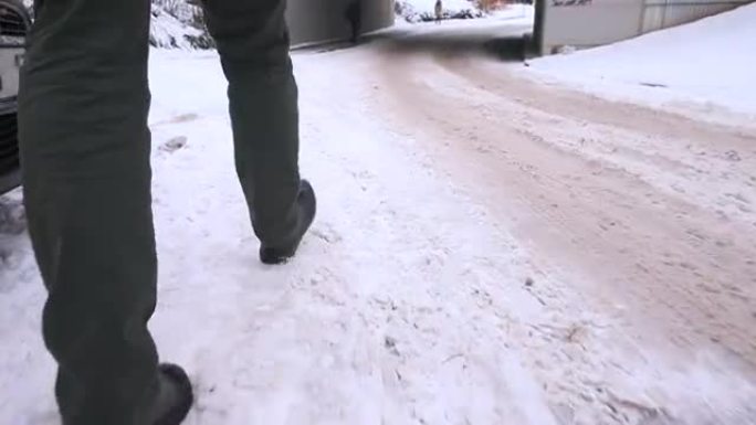 白雪皑皑的街道上的脚移动行人。他在雪地里迈出了一步。
