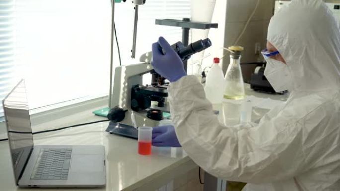 在实验室使用显微镜穿着防护服的男科学家
