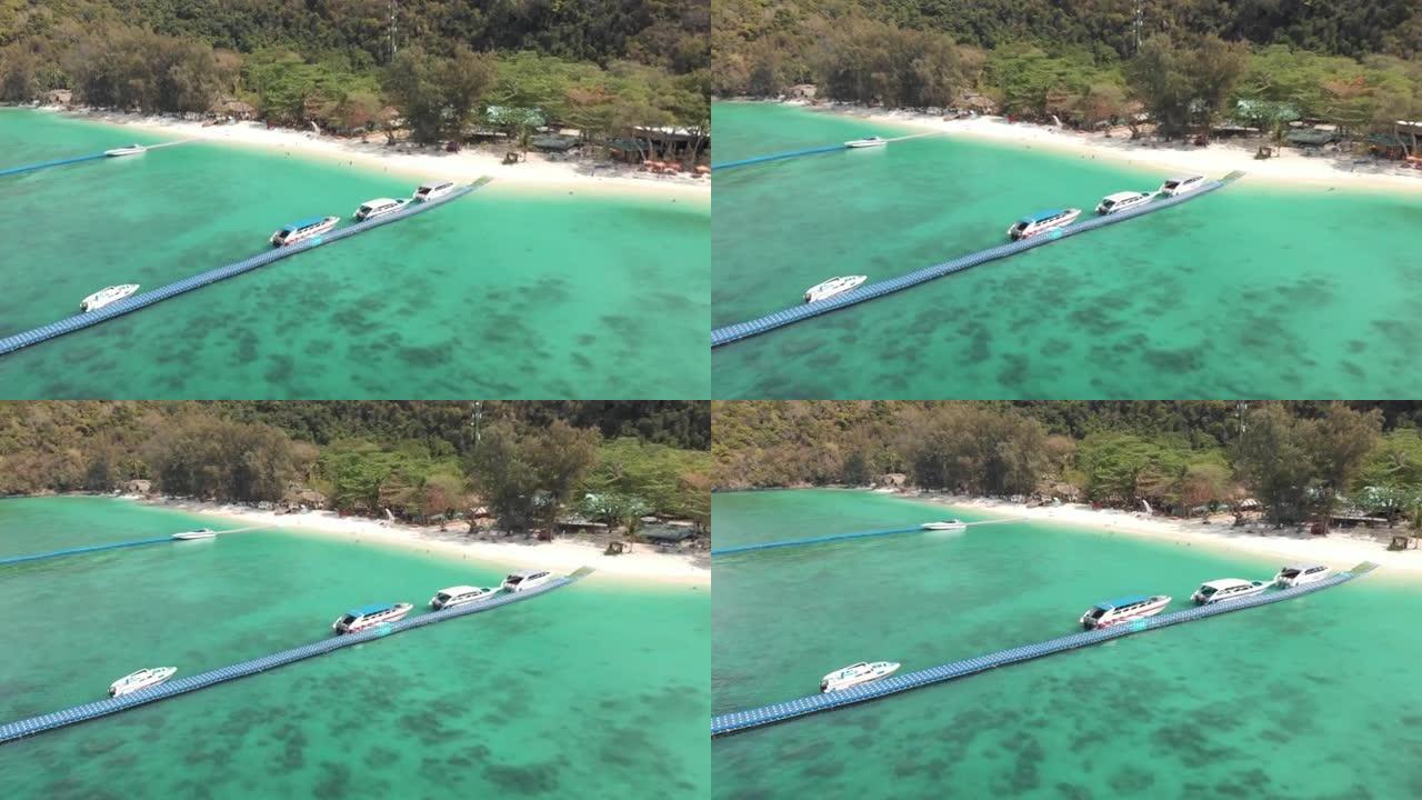 漂浮的平台码头被停泊的旅游船拥挤在泰国Koh Hey (珊瑚岛) 香蕉海滩的翡翠水上-空中飞向下降射