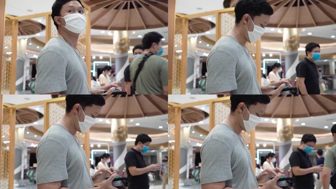 新常态 -- 亚洲男子戴着口罩在商场休息。