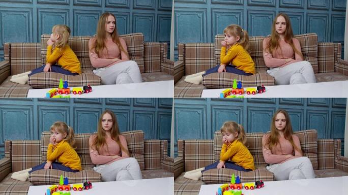 不开心的妈妈和倔强的小女儿坐在沙发上吵架后互不理睬