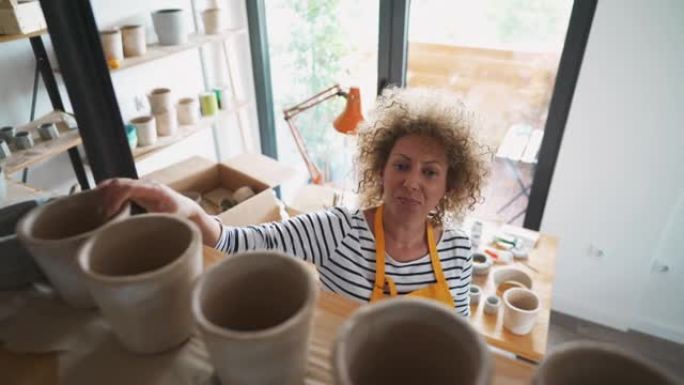 卷发艺术家在她的陶器工作室里布置着concte花盆