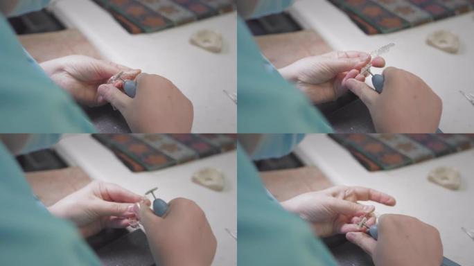 成年女性军医在实验室里制造隐形牙套。外科医生将可拆卸的隐形装置握在手中。牙科的先进技术。人造牙齿的生