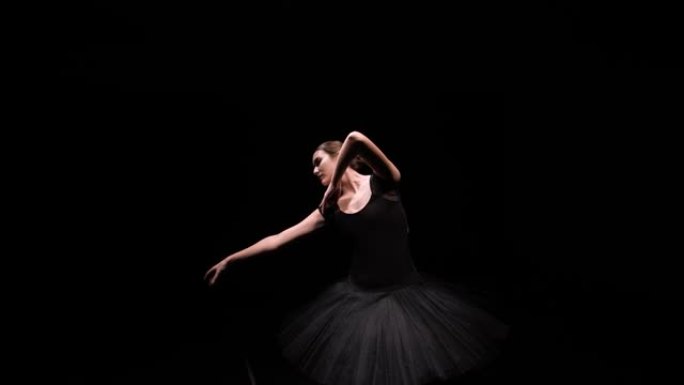 在黑色工作室背景上，黑色天鹅的图像中，芭蕾舞女演员的轨道镜头优雅地移动，并带有背光。特写。慢动作