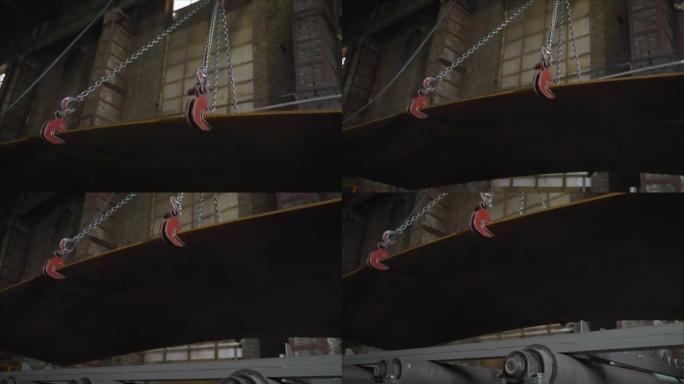 用吊梁移动重型钣金，背景是生产部门的内部。金属板在工厂用起重机吊起。冶金厂。