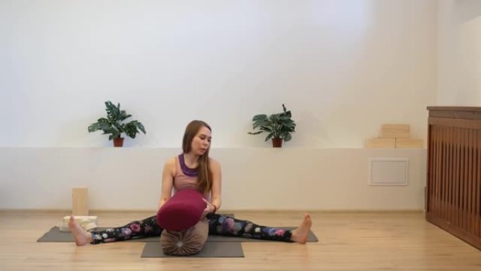 女孩瑜伽教练在工作室的垫子上使用靠垫进行课程