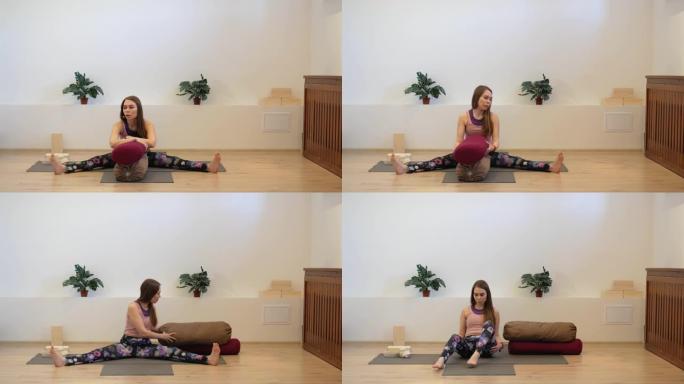 女孩瑜伽教练在工作室的垫子上使用靠垫进行课程