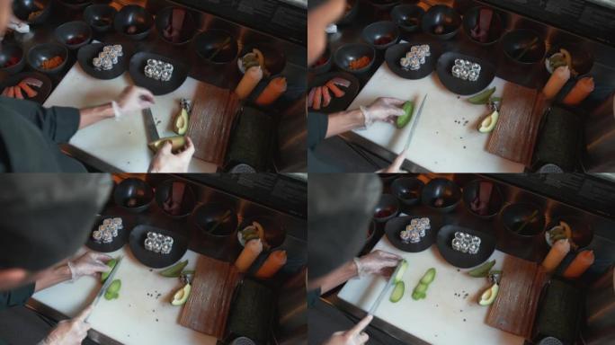 专业厨师将鳄梨切成薄片，用作寿司菜的装饰。专业厨师制作寿司调味品的俯视图