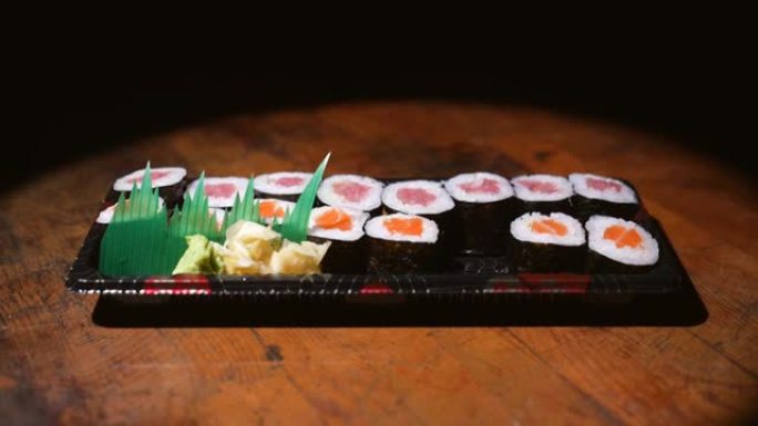 侧视图筷子拿一块三文鱼和金枪鱼寿司卷
