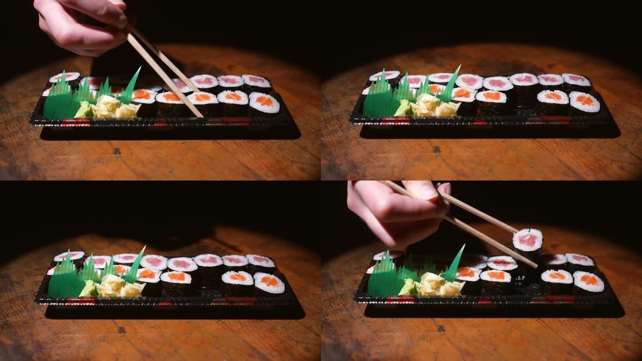侧视图筷子拿一块三文鱼和金枪鱼寿司卷