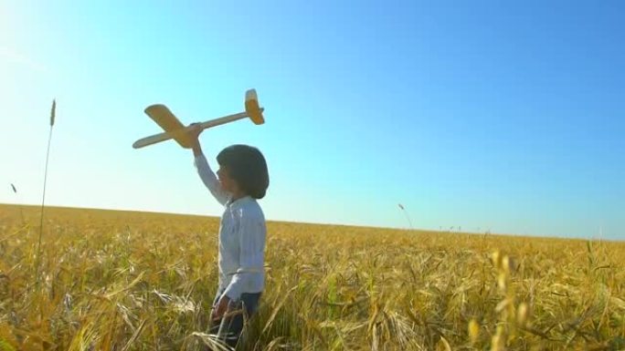 日落时，快乐的小男孩在麦田里用玩具飞机奔跑。孩子在户外夏天玩飞机。小飞行员梦想着飞行，和幸福的家人一