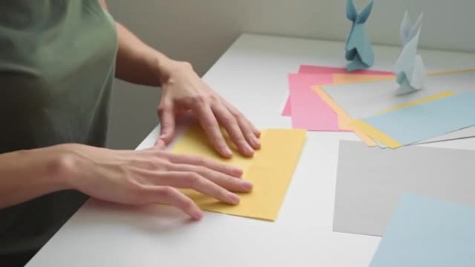 折纸课。女人用彩纸做折纸复活节兔子。DIY概念
