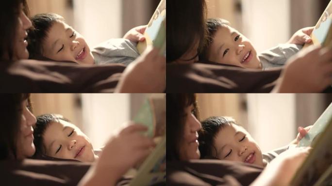 亚洲孩子和母亲在卧室里读睡前故事。家庭时间的概念