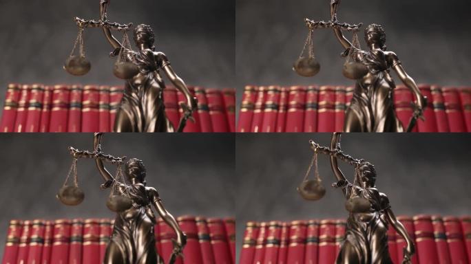 以蒙眼女神为代表的国际法律青铜象征，在一排红书前缓缓旋转，手中握着象征法律两大渊源公正与权力的平衡