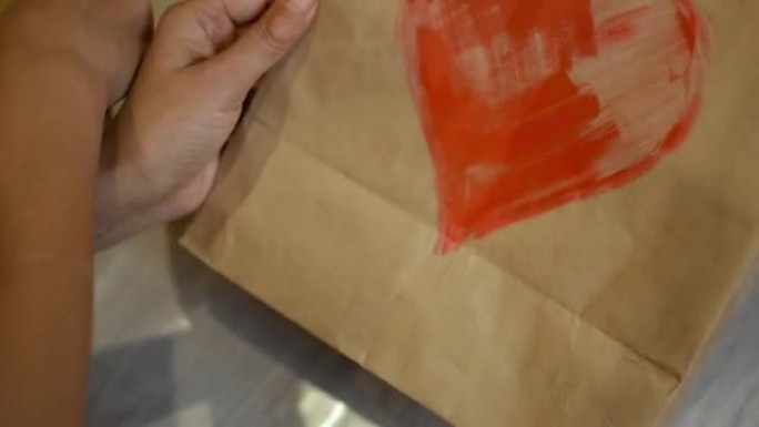 一个女孩用红色丙烯酸涂料在纸上画一颗心