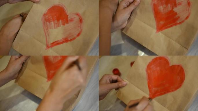 一个女孩用红色丙烯酸涂料在纸上画一颗心