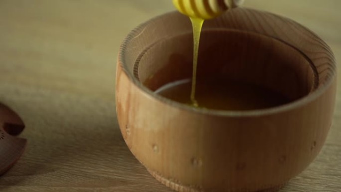 木制桌子上的木碗里的蜂蜜和木制的蜂蜜铲斗