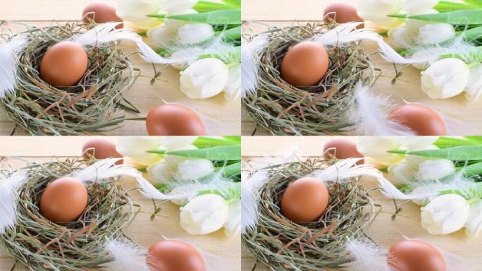 复活节符号。篮子里有春天郁金香的自然色鸡蛋，木制桌子上的白色羽毛，复活节快乐装饰。祝贺复活节设计。