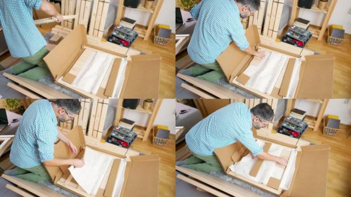 一名成年男子在家中打开装有新家具的纸板箱
