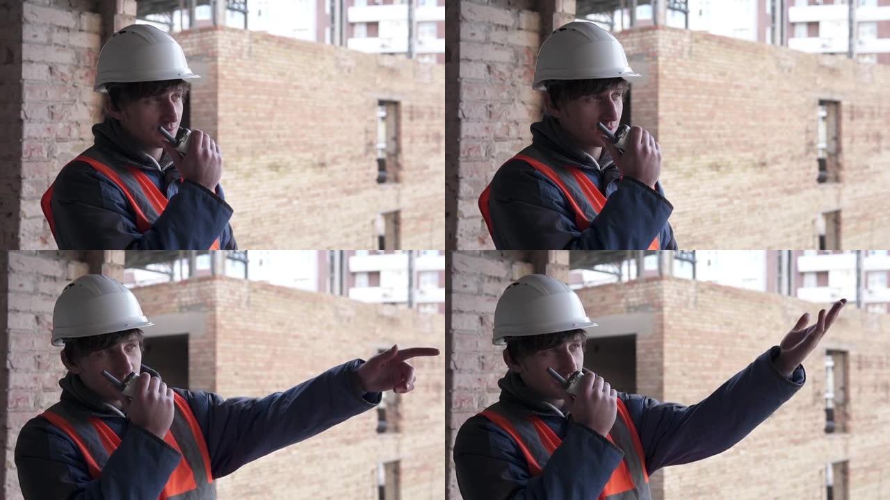 一名戴着白色防护头盔的建筑商正在用无线电对讲机进行谈判。建筑测量和建筑重建。